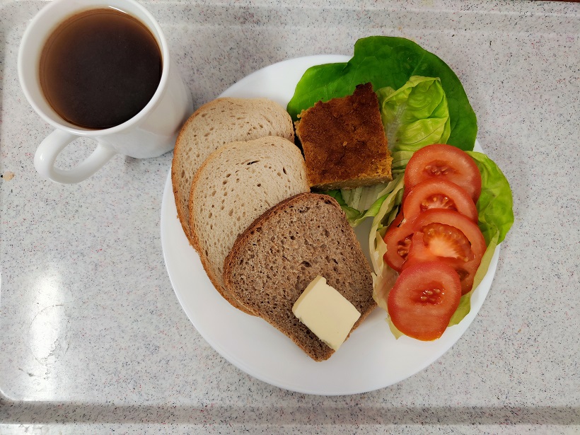Na zdjęciu znajduje się: Herbata czarna ekspresowa z cytryną Cateringowa, Chleb mieszany pszenno-żytni, Chleb Graham, Masło extra 82%, Pasztet z ciecierzycy, Pomidor, Sałata zielona